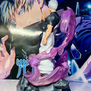May include: A detailed figurine of a character with white hair and a black shirt, standing on a base with purple and gray accents. The character is surrounded by a swirling purple energy effect. The base has the word "MAJIN" printed on it.