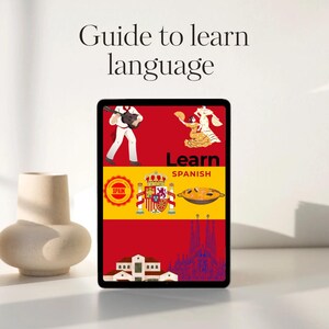 以下が含まれることがあります： スペイン語学習ガイドが表示されたタブレット。画面には、ギターを弾く人、フラメンコダンサー、パエリア、スペインの国旗、サグラダファミリアなど、スペインの文化を表す画像が表示されています。