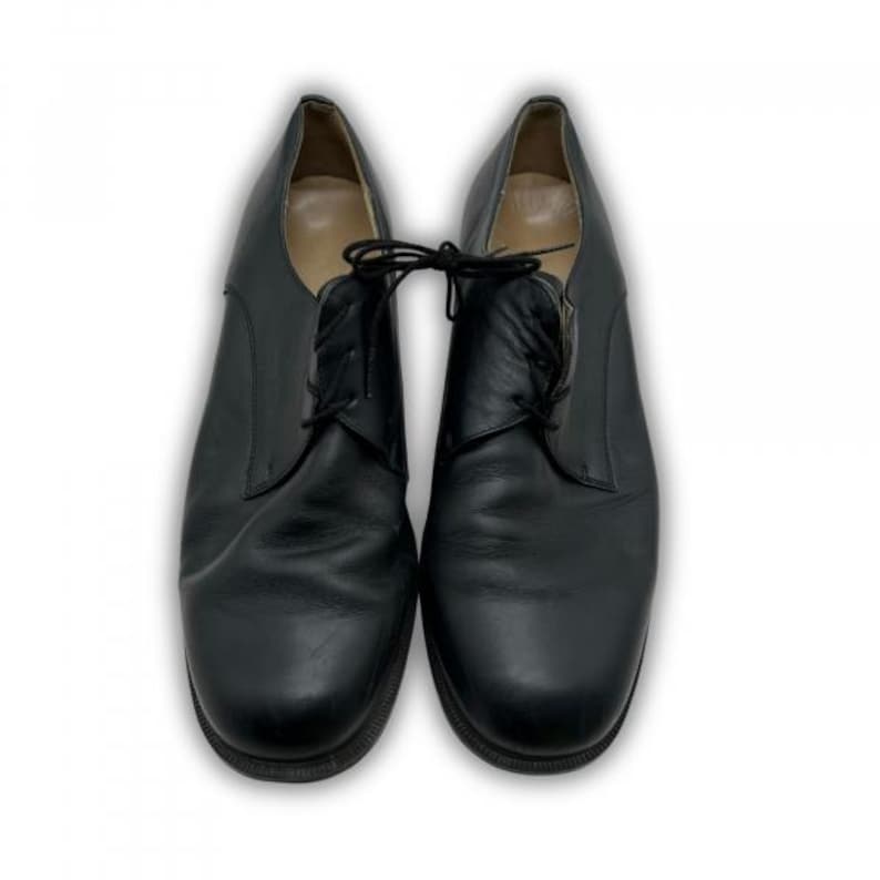 May include: A pair of black leather dress shoes with laces. The shoes have a classic design with a rounded toe and a low heel. The shoes are displayed on a white background.
