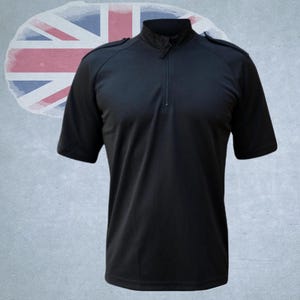 Könnte beinhalten: Schwarzes Kurzarm-Shirt mit Stehkragen und einem Viertel-Reißverschluss. Das Shirt hat Schulterklappen. Im Hintergrund ist eine verblasste Union-Jack-Flagge zu sehen.