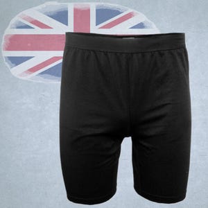 Könnte beinhalten: Schwarze Sporthose mit breitem Bund. Die Shorts sind knielang und aus einem glatten, einfarbigen Stoff gefertigt. Im Hintergrund befindet sich eine verblasste Union-Jack-Flagge.