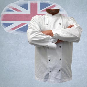 Op de afbeelding: Een witte koksjas met zwarte knopen, gedragen met gekruiste armen. De achtergrond heeft een vervaagd Union Jack vlagontwerp op een getextureerd, lichtblauw oppervlak. De jas heeft lange mouwen en een klassieke kraag.