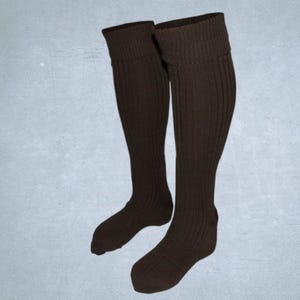 Op de afbeelding: Een paar bruine kniehoge sokken. De sokken zijn geribbeld en hebben een omgeslagen manchet aan de bovenkant. De sokken zijn gemaakt van een dik materiaal en zijn ontworpen om te worden gedragen met laarzen of ander schoeisel.