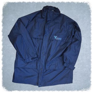May include: A navy blue waterproof jacket with a high collar and button closure. The jacket features two front pockets and the word "Interserve" printed in white on the chest.