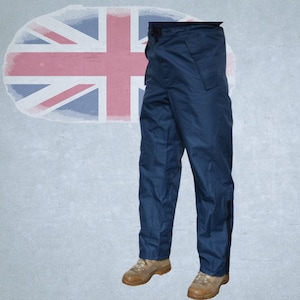 以下が含まれることがあります： ストレートレッグデザインのネイビーブルーのワークパンツ。パンツはボタンとジッパーで開閉し、サイドポケットと各脚の側面に黒いストライプが付いています。タンのワークブーツと組み合わせています。