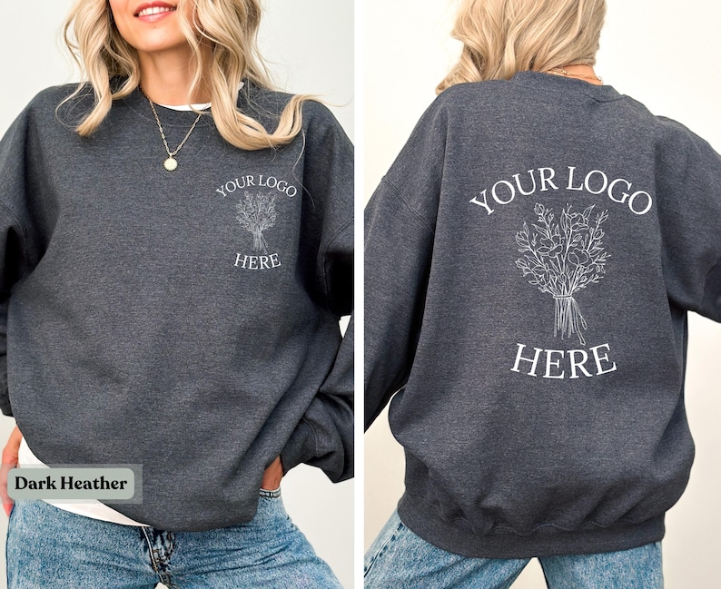 May include: Dark heather gray sweatshirt with white text and a floral design. The front of the sweatshirt has the text "YOUR LOGO HERE" and a floral design. The back of the sweatshirt has the same text and design. The bottom left corner of the image has the text "Dark Heather".