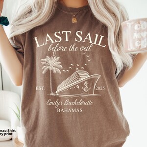 May include: Espresso brown t-shirt with an ivory print of a cruise ship, palm tree, and the text "LAST SAIL before the veil EST. 2025 Emily's Bachelorette BAHAMAS".