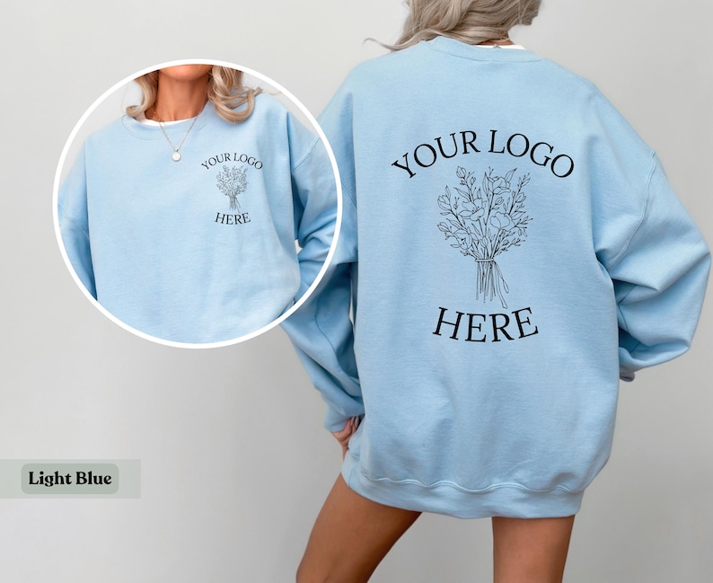 May include: Light blue sweatshirt with the text "YOUR LOGO HERE" and a floral bouquet design on the back. The front of the sweatshirt also features the text "YOUR LOGO HERE" and a floral bouquet design. The sweatshirt is a light blue color.