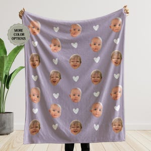 May include: A purple fleece blanket with a repeating pattern of white hearts and a baby's face.