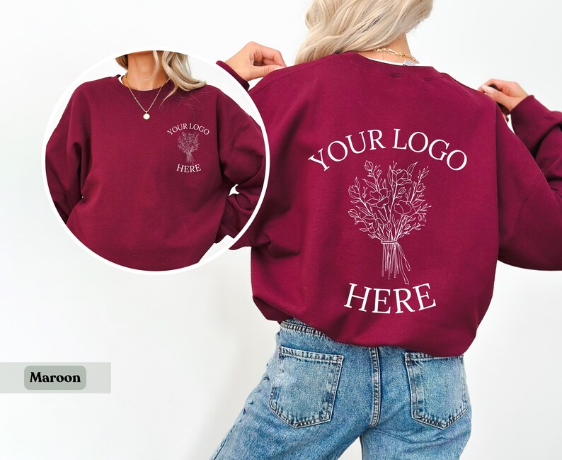May include: Maroon sweatshirt with white text and floral design. The front of the sweatshirt has the text "YOUR LOGO HERE" and a floral design. The back of the sweatshirt has the same text and design.