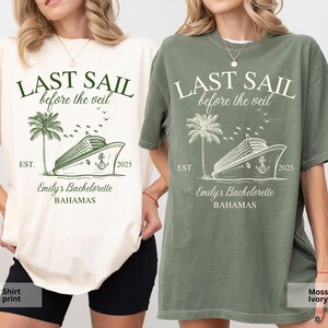 May include: Two t-shirts with a green and white design. The design features a cruise ship, palm trees, and the text "Last Sail Before the Veil" and "Emily's Bachelorette Bahamas". One shirt is ivory with a moss green print and the other is moss green with an ivory print.