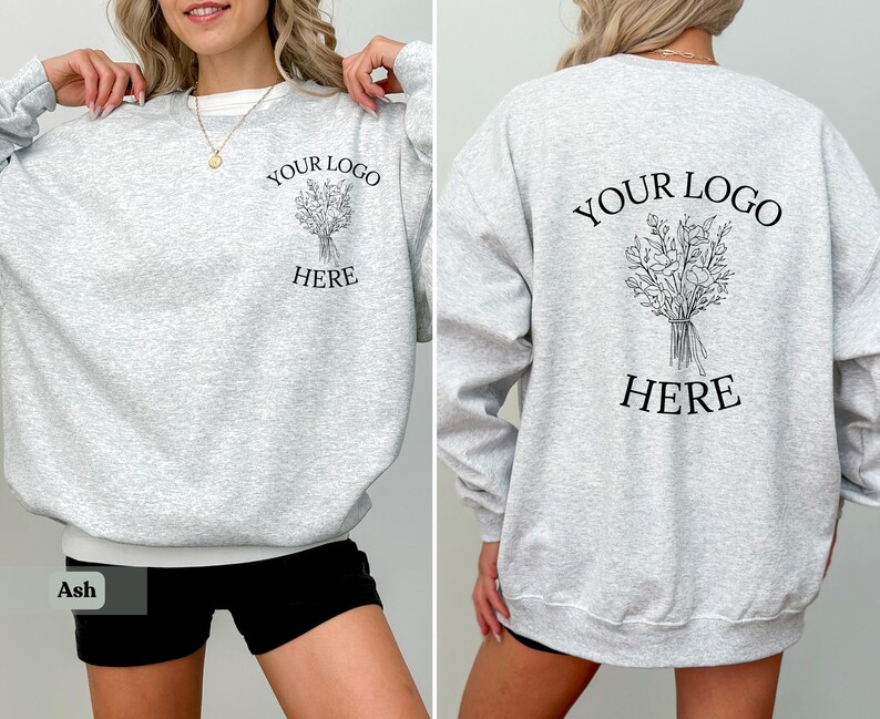May include: Light gray sweatshirt with the text "YOUR LOGO HERE" and a floral illustration on the front and back. The sweatshirt has a crew neck and long sleeves. The bottom of the sweatshirt is white.