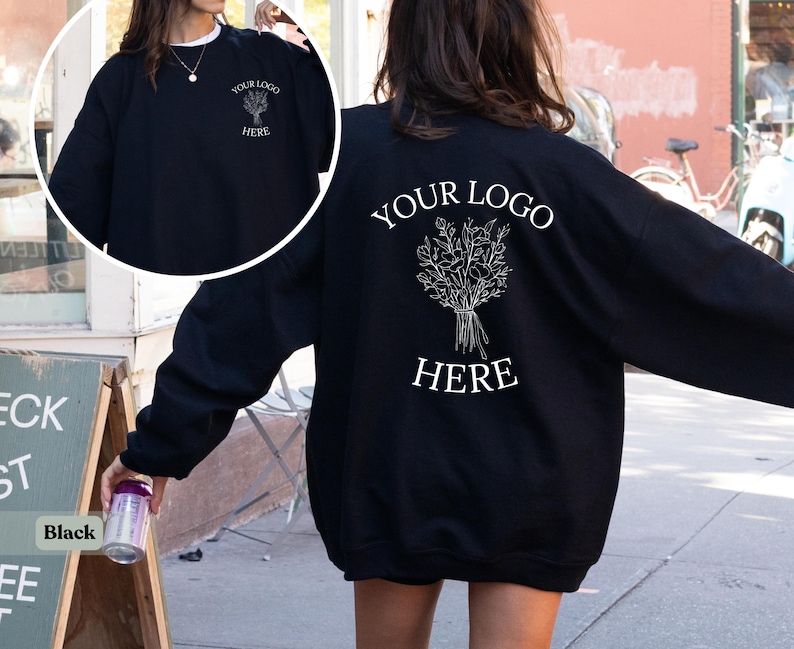May include: Black sweatshirt with white text and a floral design. The front of the sweatshirt has a small floral design and the text "YOUR LOGO HERE". The back of the sweatshirt has a larger floral design and the text "YOUR LOGO HERE".