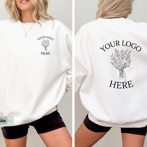May include: White sweatshirt with the text "YOUR LOGO HERE" and a floral design on the front and back. The sweatshirt is a long-sleeved crew neck style.