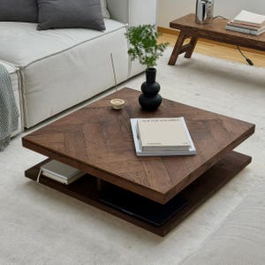 Könnte beinhalten: Ein dunkelbrauner, quadratischer Couchtisch mit Fischgrätmuster. Der Tisch hat ein unteres Regal und beherbergt Bücher, eine schwarze Vase mit Grün und einen kleinen Räucherstäbchenhalter. Der Tisch befindet sich in einem modernen Wohnzimmer.