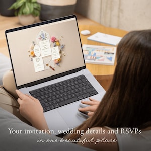 Person sits on a sofa holding a laptop displaying the wedding website with a floral envelope and invitation cards for "Anna and Thomas." Caption below reads "Your invitation, wedding details and RSVPs in one beautiful place."