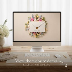 Desk with a monitor displaying a cream floral envelope with a gold wax seal reading "Tap to open," alongside a keyboard, mouse, and glasses. Caption below: "View the website demo – link in description," with an arrow.