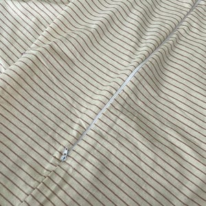 a close-up view of a striped fabric, with a zipper visible in the center.