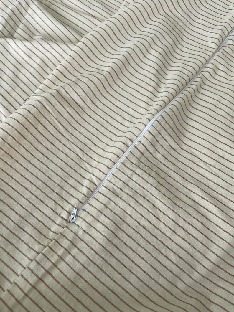 a close-up view of a striped fabric, with a zipper visible in the center.