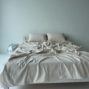 a bed with a white bedspread and pillows, and a silver disco ball is placed on the floor next to the bed.