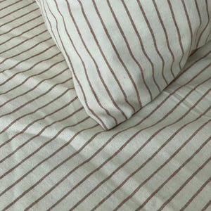 a close-up view of a bed with striped bedding, including a pillow and sheets.