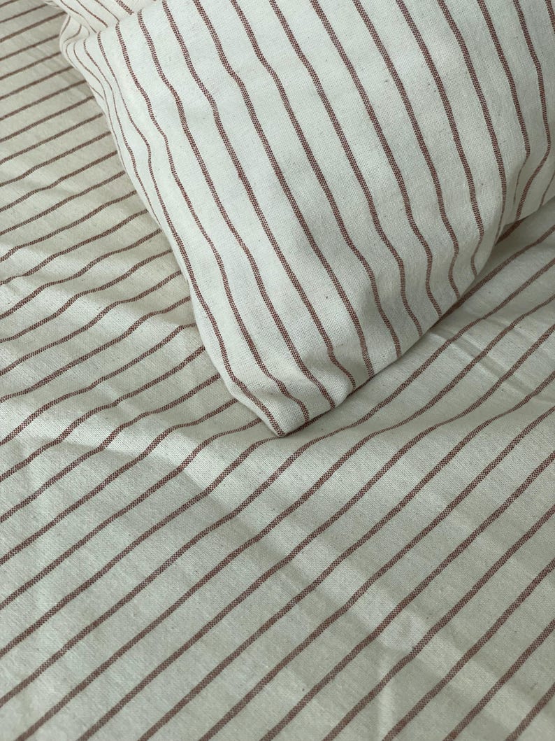 a close-up view of a bed with striped bedding, including a pillow and sheets.