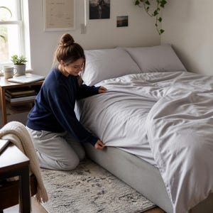 May include: A light gray duvet cover set on a bed, featuring a smooth, solid-colored fabric. The bedding includes a matching duvet cover and two pillows, creating a clean and uniform appearance for the bed frame and mattress setup.