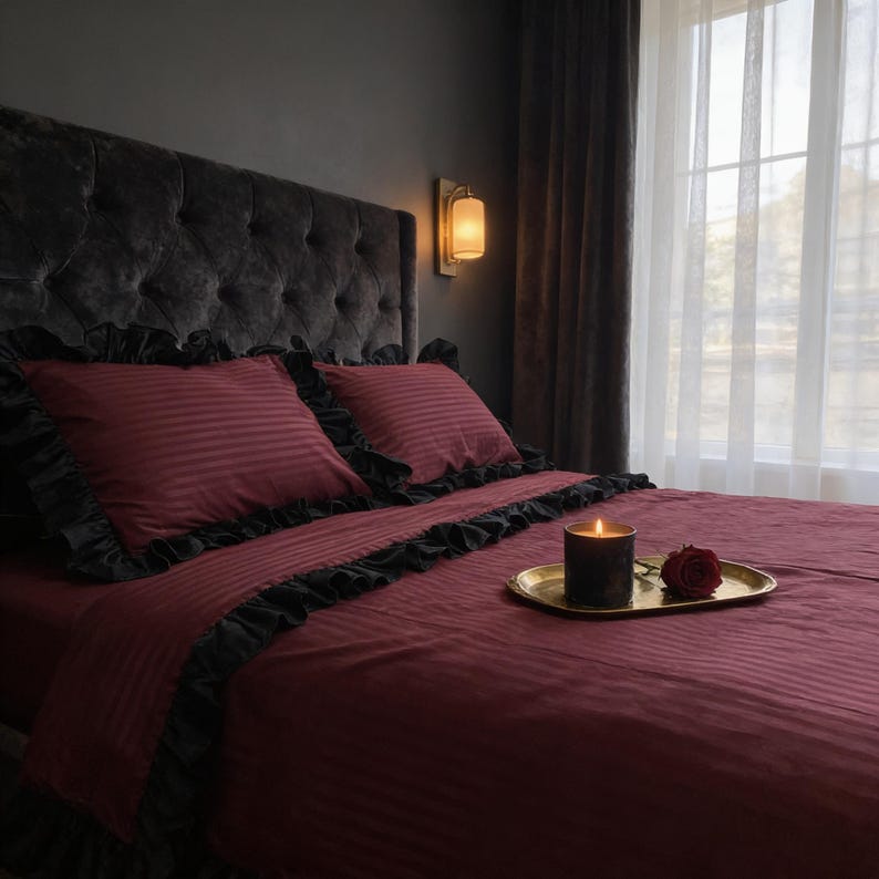 A cozy bedroom scene with a tufted headboard, a red bedspread, and a lit candle on a tray.
