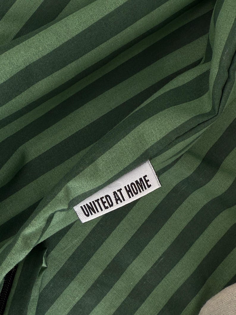 A close-up view of a green and black striped fabric with a white label that reads "UNITED AT HOME".
