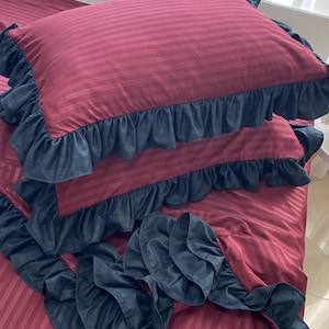 a bed with a red and black striped comforter and matching pillows with ruffled edges.