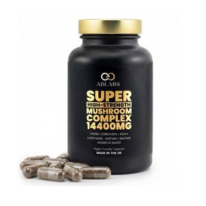 Könnte beinhalten: Eine schwarze Ergänzungsmittelflasche mit goldenem Deckel und goldener Schrift, die "SUPER HIGH-STRENGTH MUSHROOM COMPLEX 14400MG" lautet. Mehrere Kapseln sind vor der Flasche verstreut. Auf der Flasche steht auch "Vegan Friendly Capsules MADE IN THE UK."