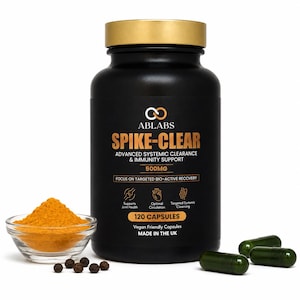 May include: A black plastic bottle with a gold lid labelled ABLABS SPIKE-CLEAR 500MG 120 CAPSULES. Beside it sits a clear glass bowl filled with yellow powder, five black peppercorns, and three dark green capsules on a white surface.
