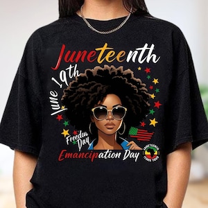 May include: Black t-shirt featuring a graphic of a woman with sunglasses and an afro. The text reads "Juneteenth 19th June" and "Freedom Day Emancipation Day". The design includes stars and an American flag.