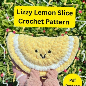 Puede incluir: Una rodaja de limón hecha a mano con un rostro sonriente y pequeñas piernas rosas. El limón es amarillo con una cáscara blanca y ojos bordados negros. El texto en la imagen dice "Lizzy Lemon Slice Crochet Pattern" y "Pdf Pattern".