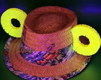 May include: A straw hat with a patterned band and two yellow pineapple-shaped decorations. The hat has a woven texture and a colorful band with a tropical design. The text "Hat Not Included" is at the bottom.
