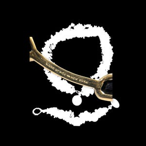 May include: Gold-toned Kate Spade New York bracelet. The bracelet has a curved design with a black center and a small charm. The brand name is engraved on the side of the bracelet.