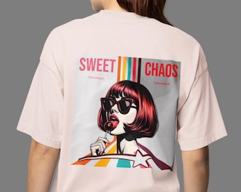 Puede incluir: Camiseta rosa claro con un diseño pop art en la espalda. El diseño muestra a una mujer con pelo rojo y gafas de sol, sosteniendo una piruleta, con las palabras "SWEET CHAOS" arriba. La camiseta tiene mangas cortas.