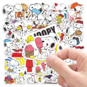 May include: A collection of die-cut vinyl stickers featuring the white beagle Snoopy and the yellow bird Woodstock in various poses and activities, including eating pink ice cream, wearing hats, and playing sports, with bold black outlines.