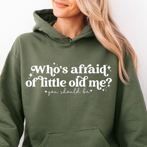 May include: A green hooded sweatshirt with the text "Who's afraid of little old me? You should be" in white lettering.