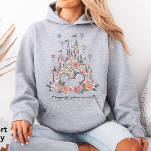 May include: A gray hoodie with a floral design of a castle and the text "Happiest place on earth".