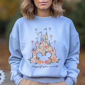 May include: Light blue sweatshirt with a floral design of a castle and the text "Happiest place on earth".