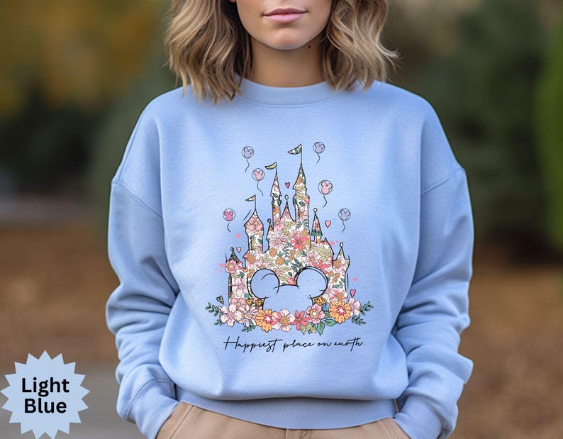May include: Light blue sweatshirt with a floral design of a castle and the text "Happiest place on earth".