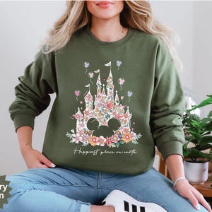 May include: A green sweatshirt with a floral print of a castle and the text "Happiest place on earth".