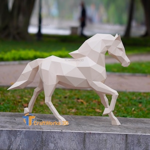 May include: A geometric, off-white paper horse sculpture in a running pose. The sculpture is made of many flat, triangular planes, giving it a faceted appearance. The sculpture is on a concrete surface with grass and trees in the background. The text "TCraftWorks 3D" is visible.