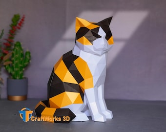 Op de afbeelding: Een geometrisch papieren kattenbeeld in een zittende positie. De kat heeft een lapjespatroon met zwarte, oranje en witte delen. Het beeld is gemaakt van gevouwen papier en heeft een driedimensionaal uiterlijk. Het CraftWorks 3D-logo is zichtbaar.