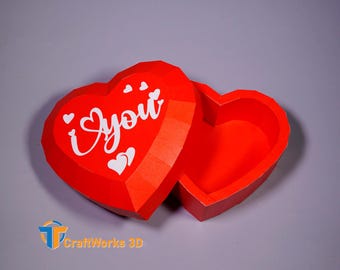 May include: Red paper heart-shaped box with a lid that opens to reveal an empty interior. The lid has the words "I ♥ you" printed in white.