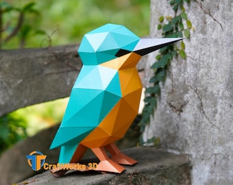 May include: A geometric papercraft kingfisher sculpture in teal, orange, and brown. The bird is perched on a stone surface, with a black beak and the text "CraftWorks 3D" visible. The sculpture is a unique piece of home decor.