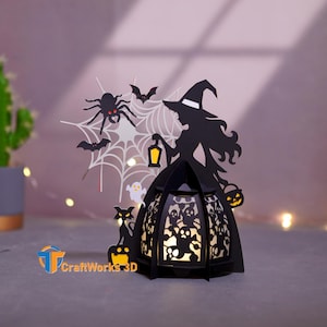 May include: A black Halloween-themed paper lantern featuring a witch silhouette, spider web, bats, and a cat. The lantern has a cut-out design with a light inside, creating a spooky ambiance. The lantern is decorated with a pumpkin and a ghost.