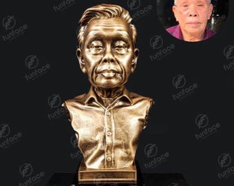 Puede incluir: Una escultura de busto de color dorado de una persona con un rostro realista y una camisa blanca. El busto está sobre una base negra.