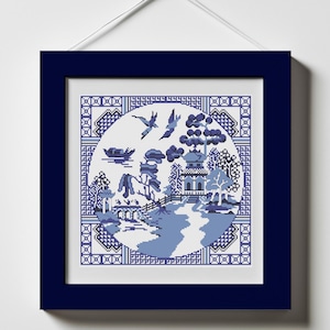 May include: A framed blue and white cross-stitch design of a traditional Chinese landscape with a pagoda, trees, a bridge, and birds. The design is surrounded by a blue border with a repeating pattern.